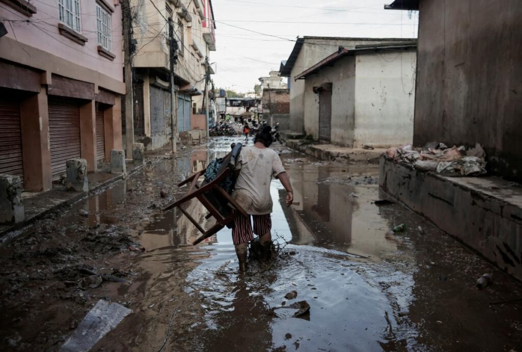 A woman carrying a chair walks along a muddy street as the floodwater recedes from a residential area that was flooded by the overflowing Bagmati River following heavy rains in Kathmandu, Nepal September 29, 2024. REUTERS/Navesh Chitrakar