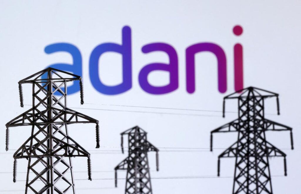 Electric power transmission pylon miniatures and Adani Green Energy logo are seen in this illustration taken, December 9, 2022. REUTERS/Dado Ruvic